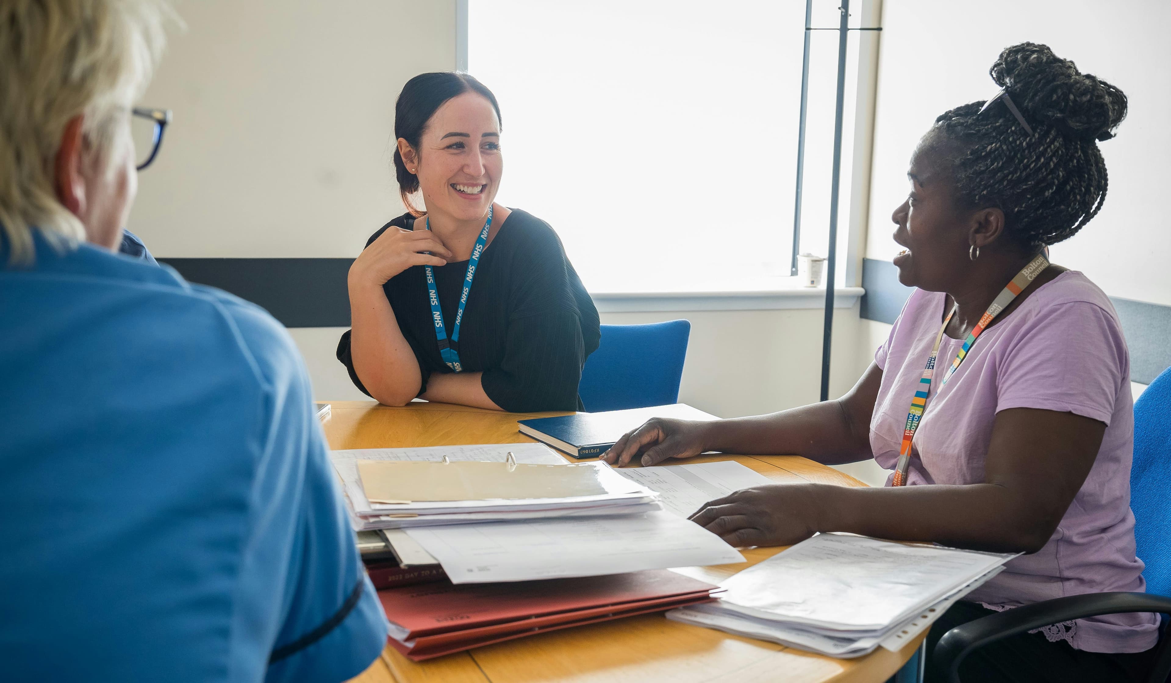 Employees sitting around a table, documents in front of them.
