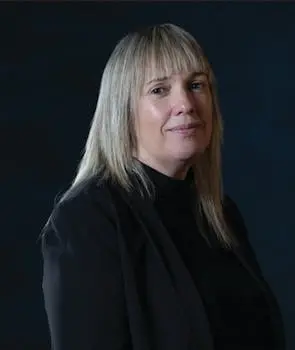 Blonde woman in front of a dark blue background.