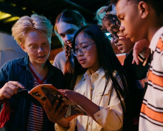 Group of young people looking at a magazine together.