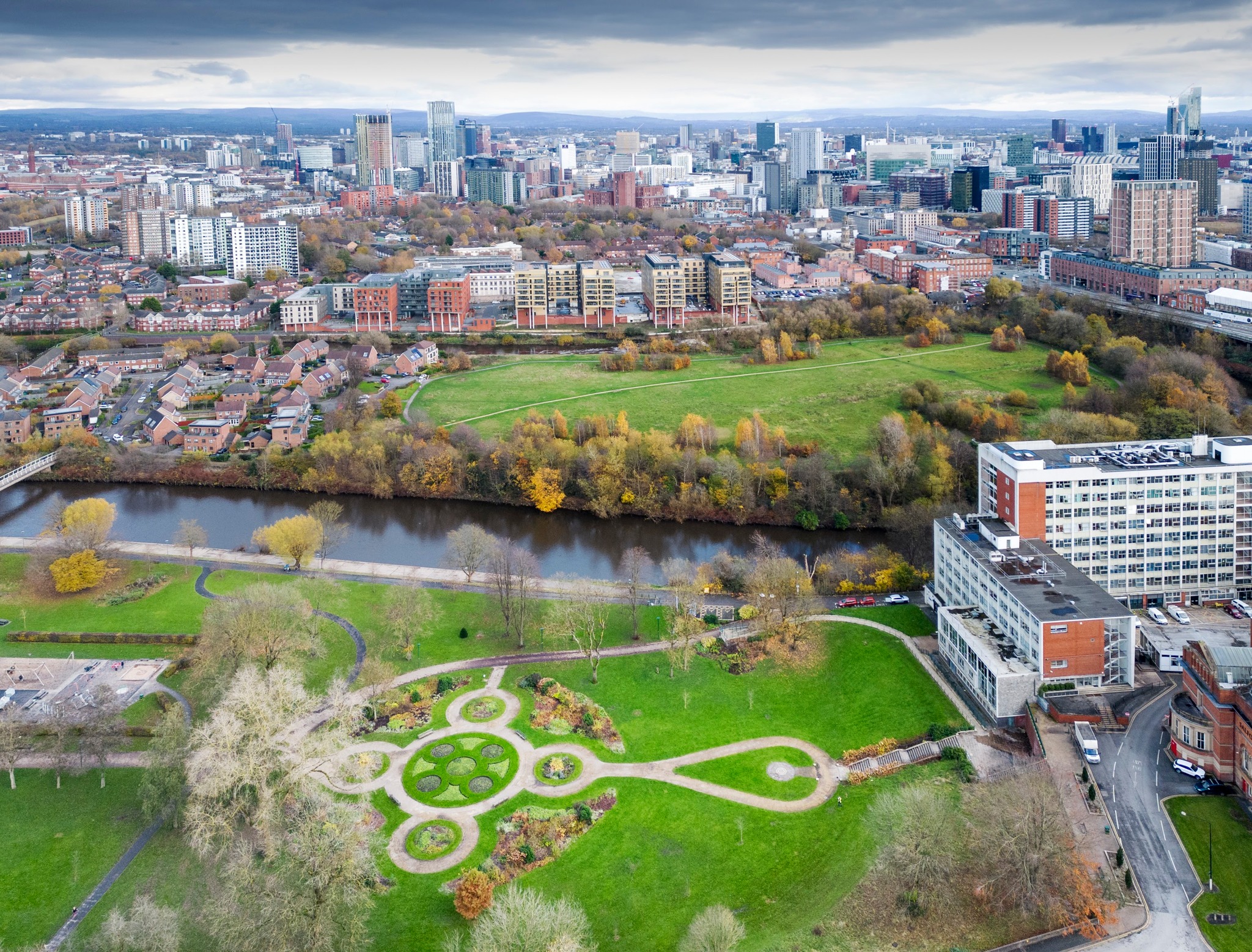 Overhead view of Salford, England with a river, buildings, and green space.