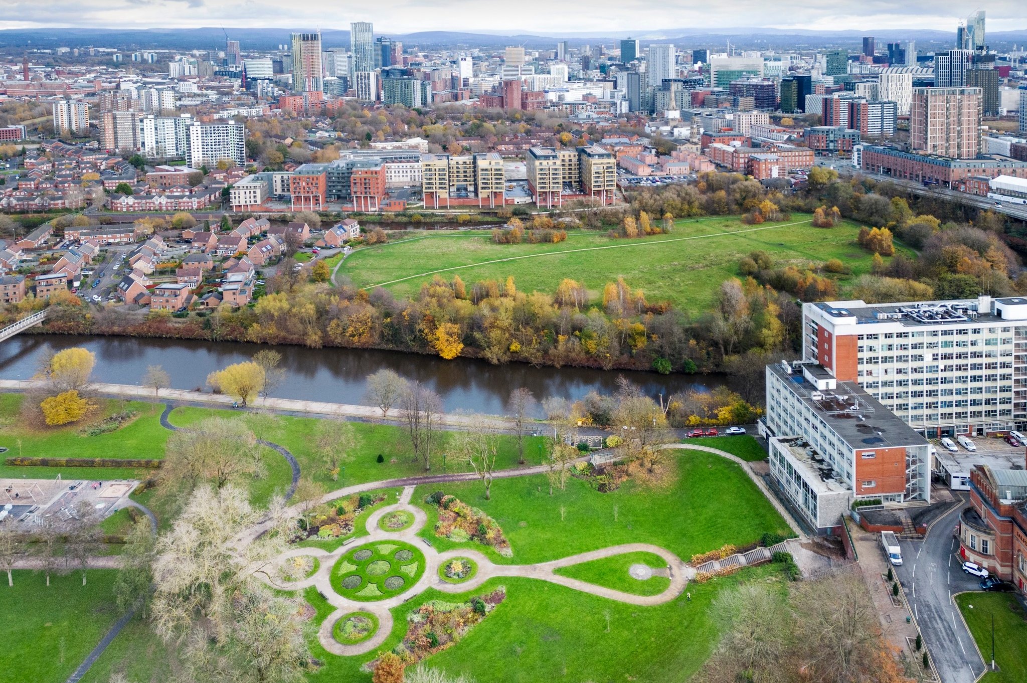 Overhead view of Salford, England with a river, buildings, and green space.