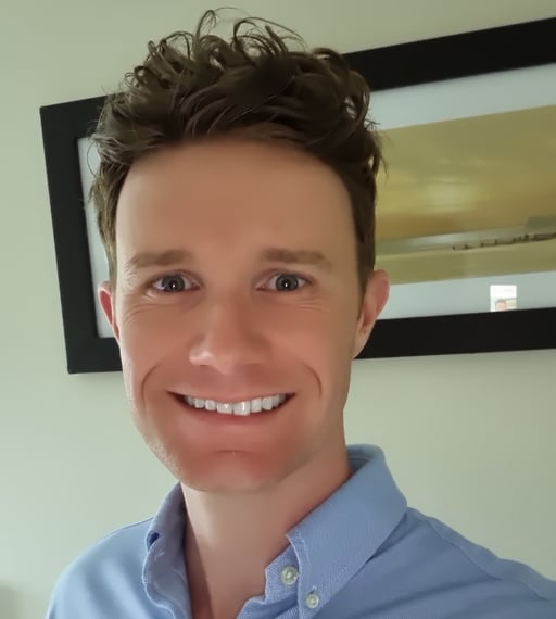 Smiling man in a blue button-down shirt, looking at the camera.