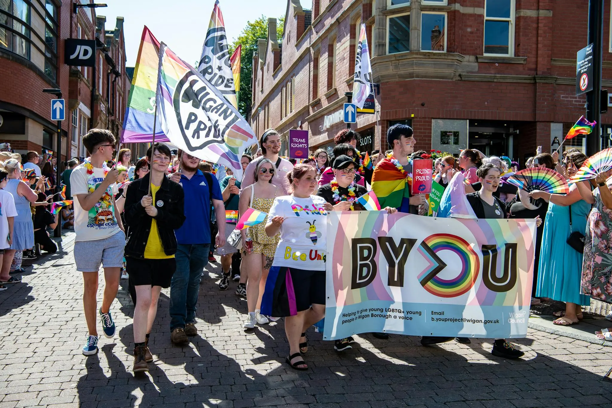 People marching in a pride parade, flags and banners are held up.