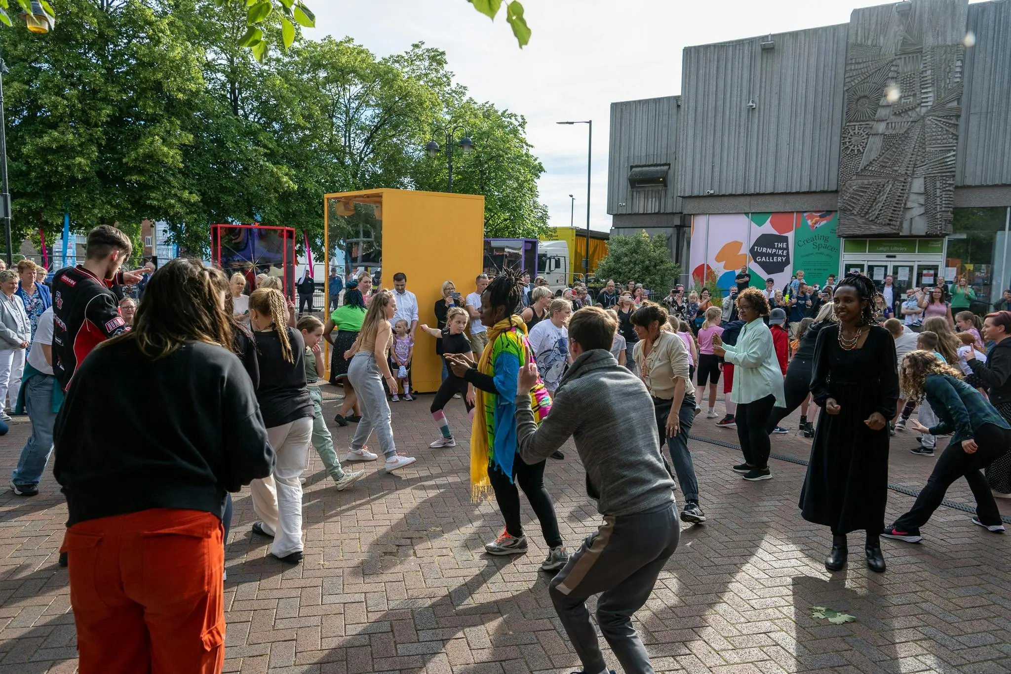 People dancing outdoors, building in background.