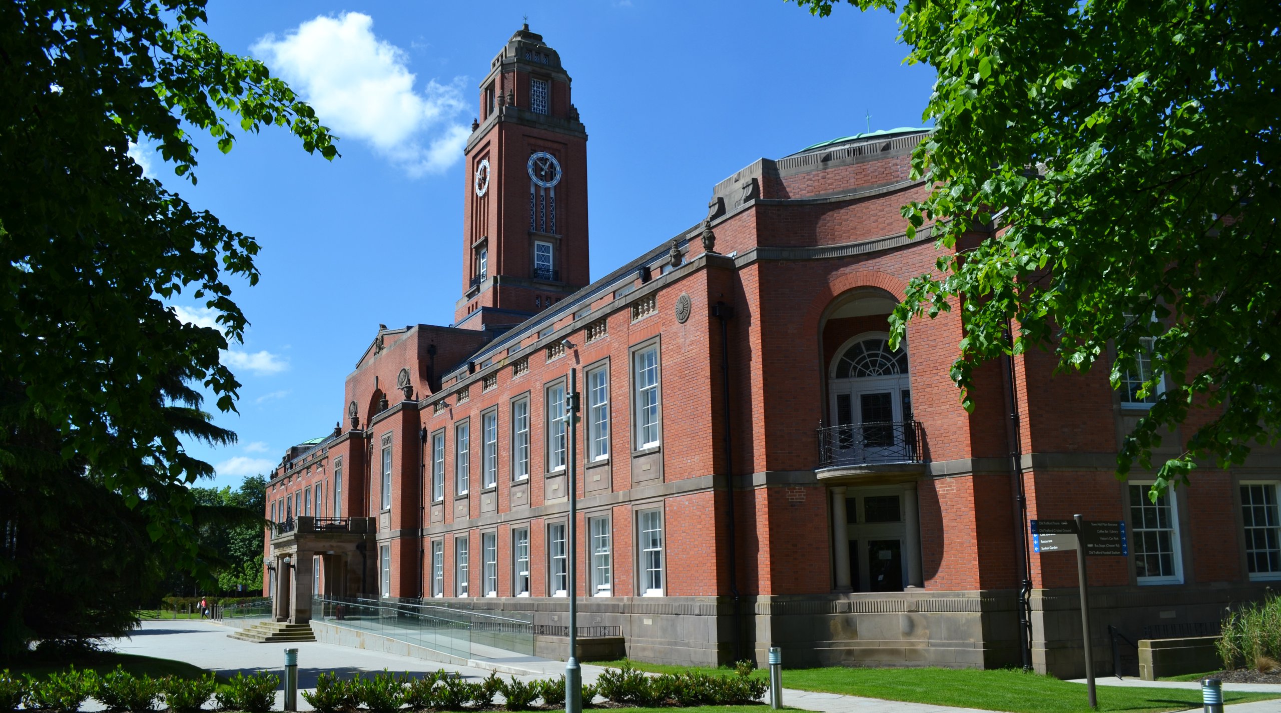 Red brick building with clock tower and trees.