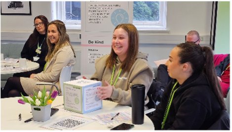 People seated at a table, smiling and engaged in conversation.