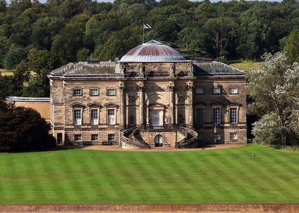 Historic house with a domed roof and large lawn. Trees in the background.