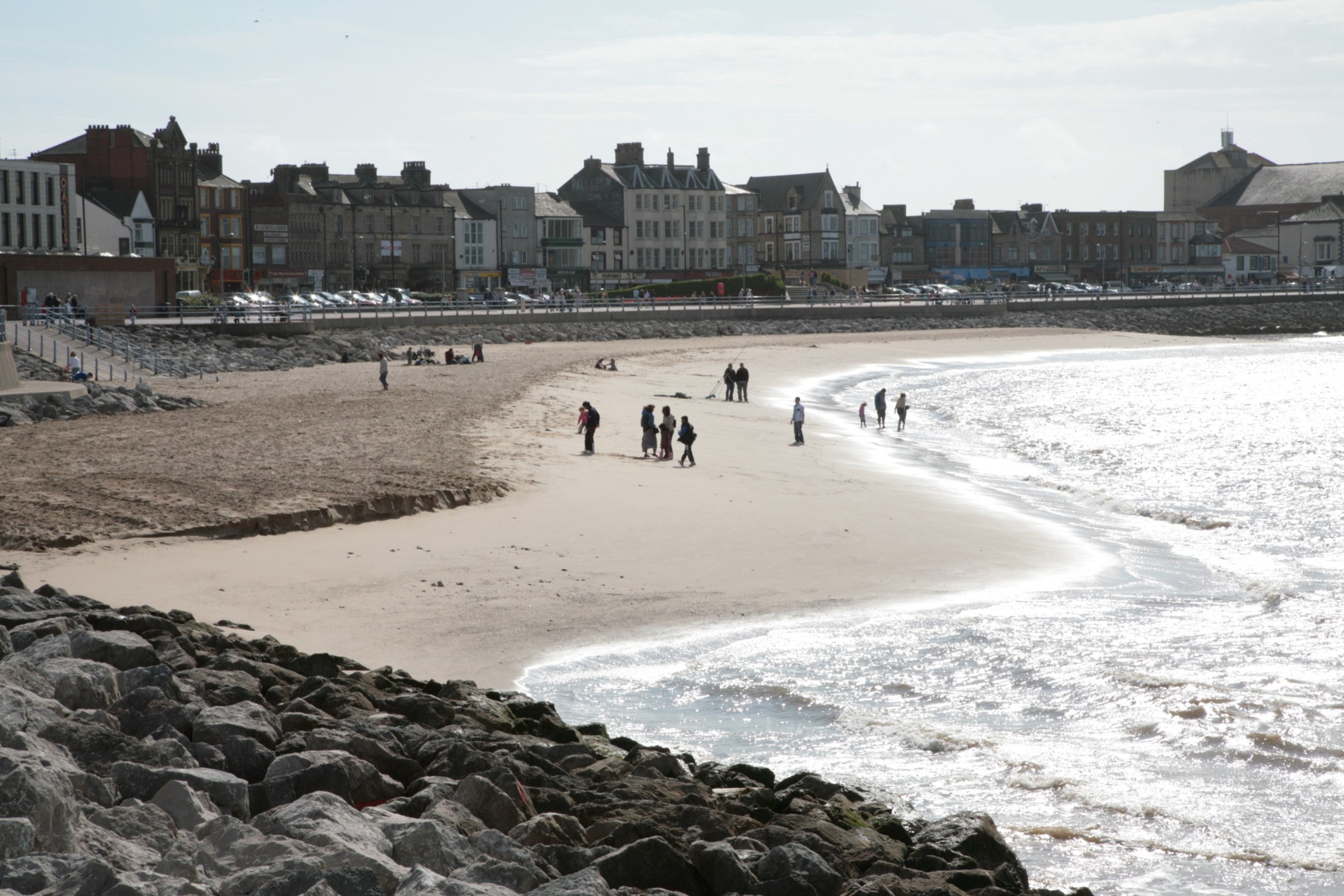 Beach with people, buildings in background.