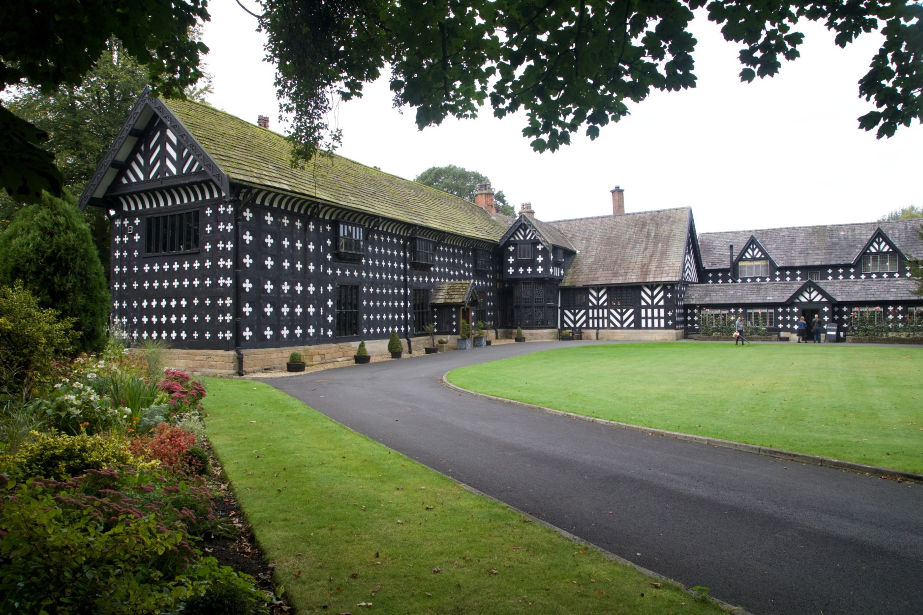 Black and white building with a road and green lawn.