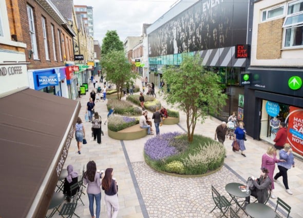 Pedestrianized street with shops, trees, and seating areas.