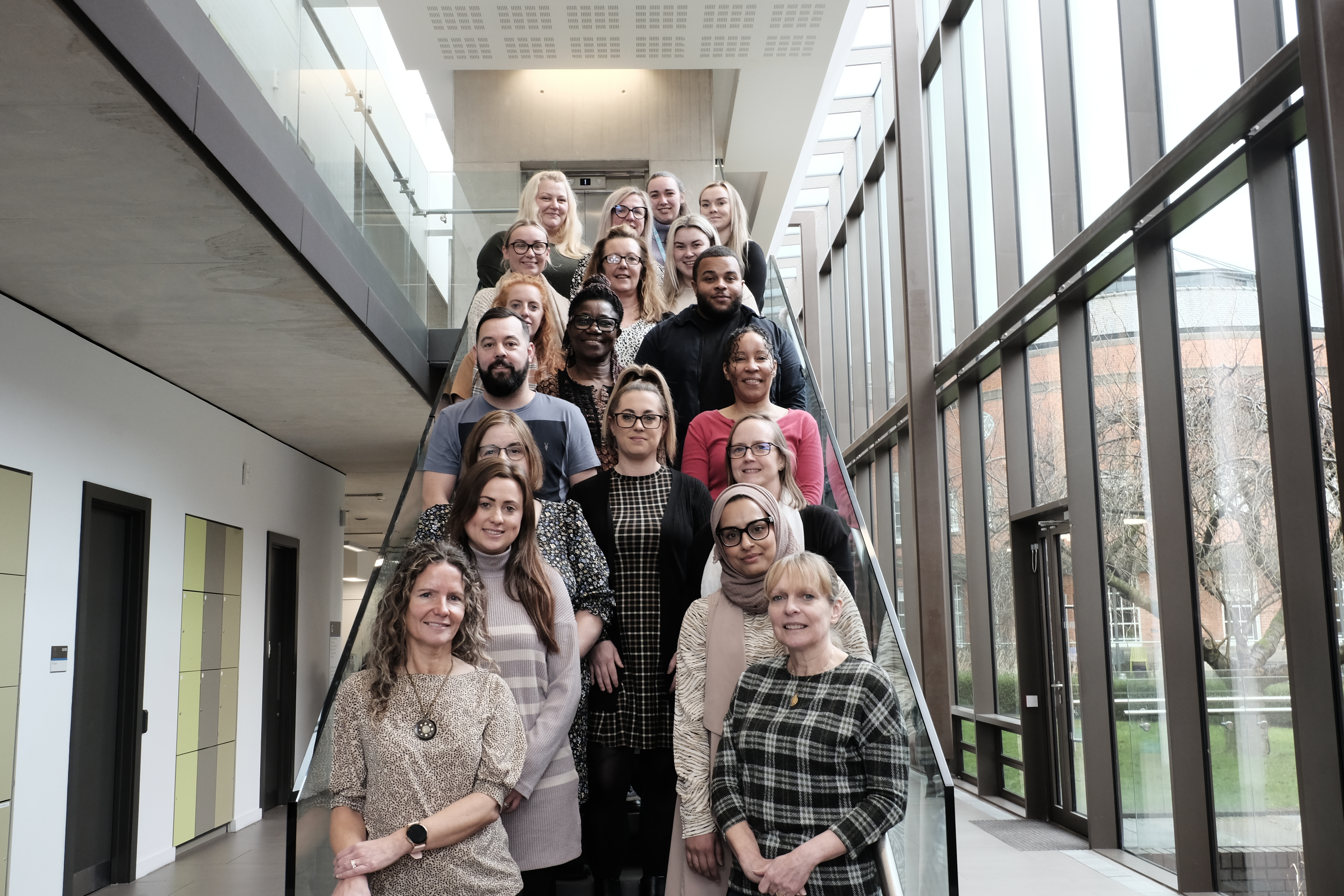 Group of diverse people standing on stairs indoors.