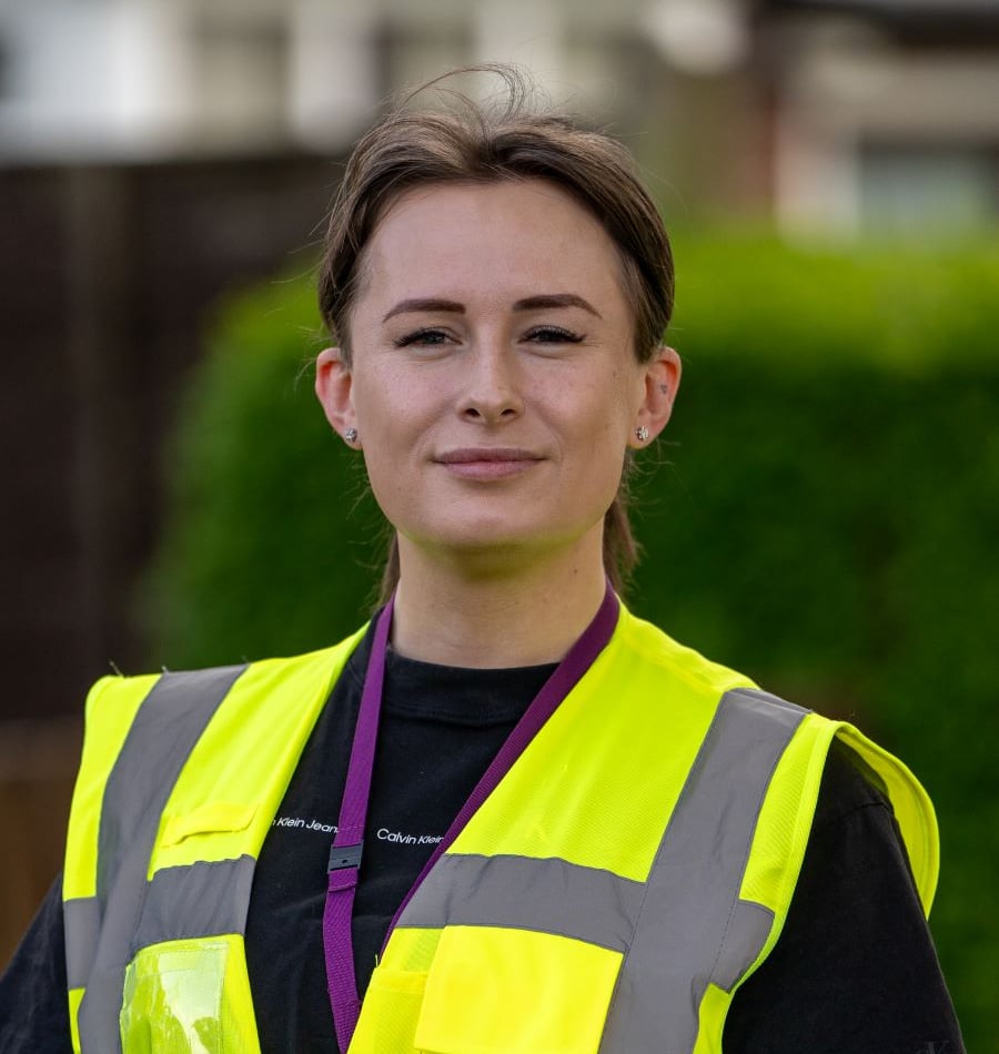 Portrait of Sophie wearing a high-vis vest for work.