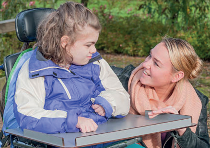 A woman and girl with special needs outdoors.