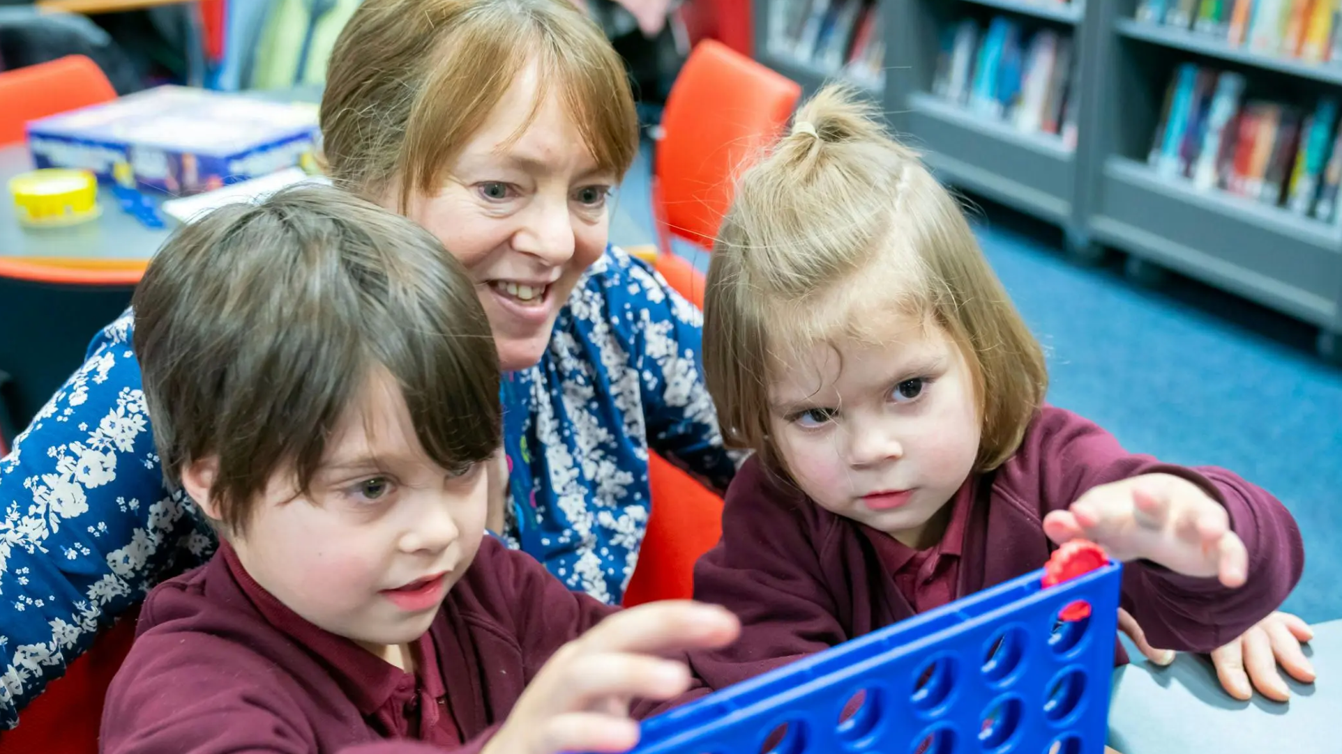 A woman and two kids playing a game together.