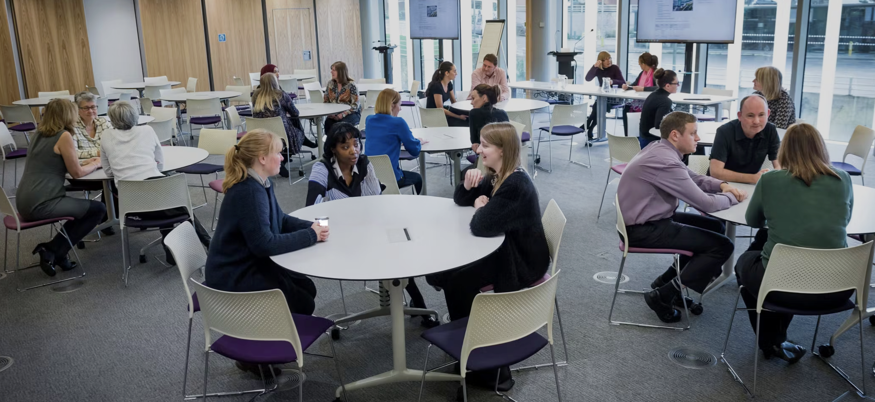 People sitting at tables in a modern meeting room.