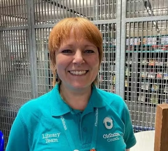 Woman wearing teal shirt, "Library Team" and "Oldham Council"