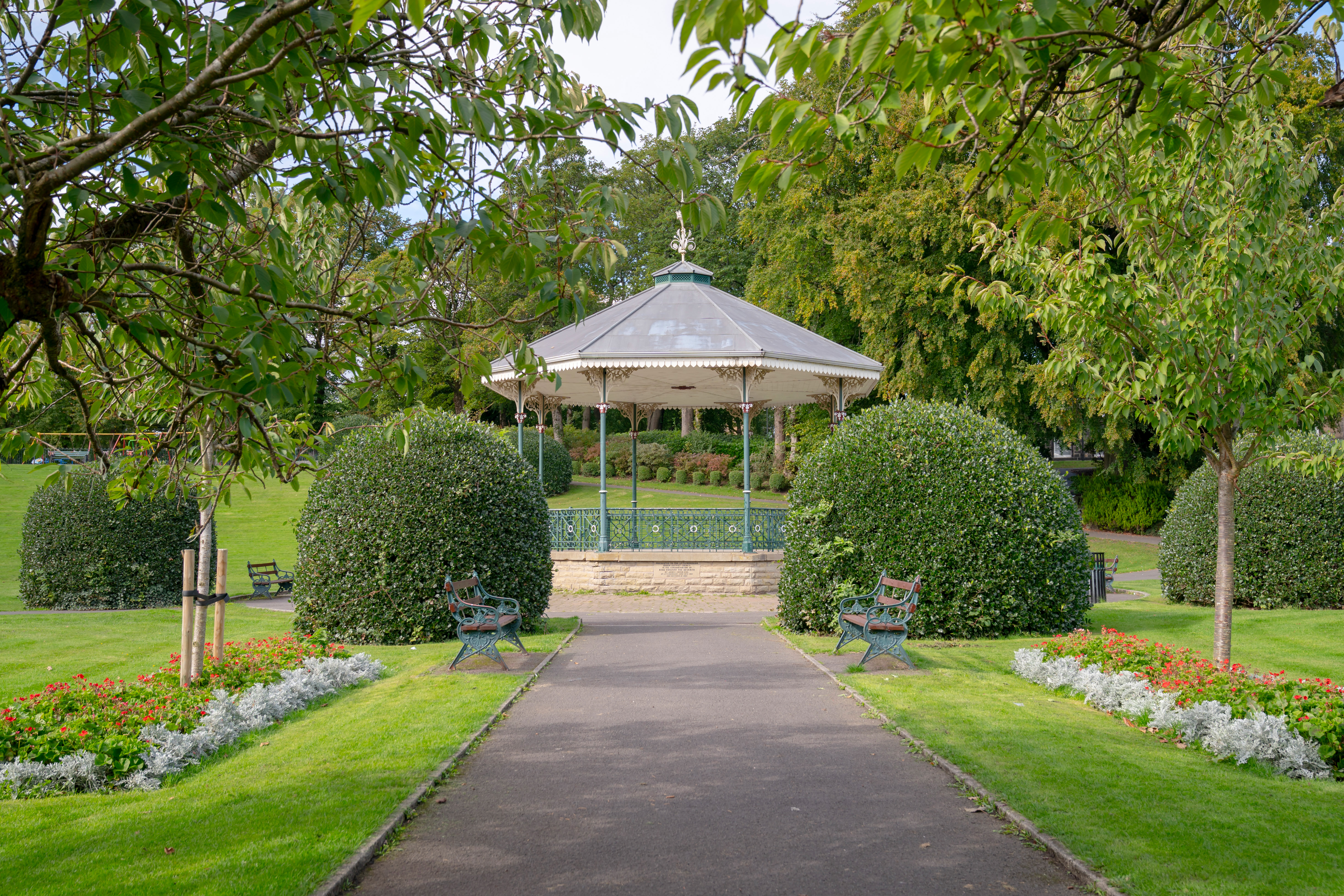 Gazebo, garden beds, benches in a park setting.